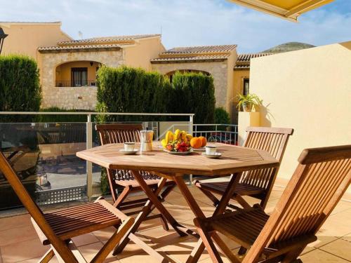 - une table en bois avec des chaises et une corbeille de fruits sur la terrasse dans l'établissement Apartamento Pàmpol, à Lliber