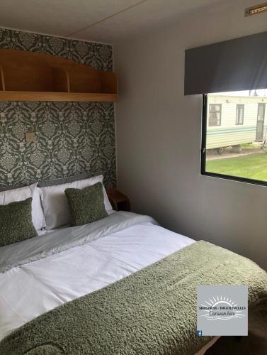a bedroom with a large bed with a window at Skegness - Ingoldmells Caravan Hire in Ingoldmells