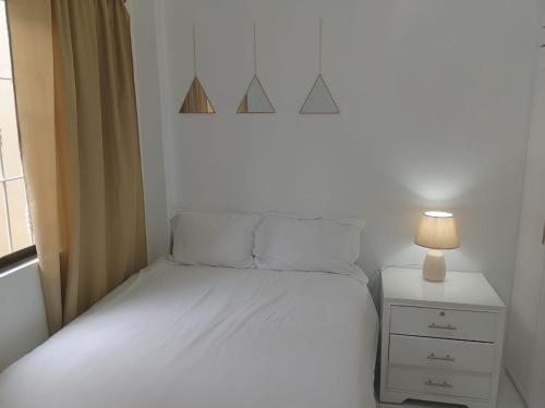 Dormitorio pequeño con cama blanca y lámpara en Comfortable 3-Bedroom Condo in Bellavista, Guayaquil en Guayaquil