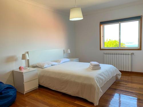 een slaapkamer met een wit bed en een raam bij Miracaminha in Caminha
