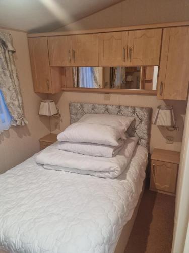 a bed in a small room with wooden cabinets at Discover comfort home from home 8-birth Caravan in Skegness