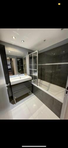 une grande salle de bain avec une baignoire et un lavabo dans l'établissement T3 collines niçoises au calme avec stationnement privatif, à Nice