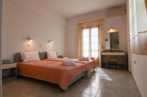 1 dormitorio con 1 cama grande con manta naranja en Chrys Marie Studios, en Iräon