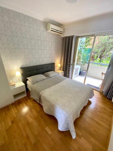 une chambre avec un grand lit et une grande fenêtre dans l'établissement Le Panomagique, à Villefranche-sur-Mer