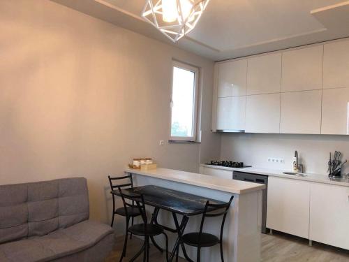 a kitchen with white cabinets and a bar with stools at Guest House Bagrationi in Batumi