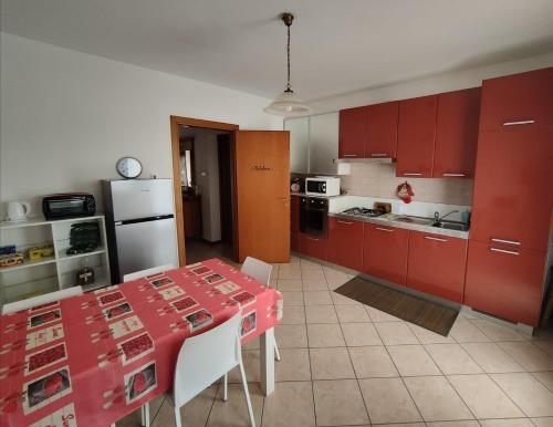 una cocina con armarios rojos y una mesa con sillas. en Dolce Ricordo, locazione turistica, en Marano Vicentino