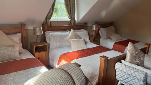 a attic room with three beds and a chair at Heeneys Lodge B&B in Donegal