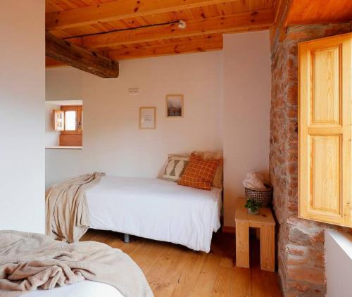 1 dormitorio con 2 camas y pared de ladrillo en 201A La Huerta de Cayao, en Villaviciosa