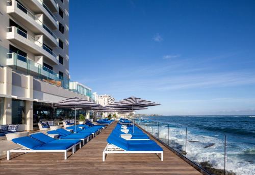 a row of blue beach chairs and umbrellas on the beach at Condado Vanderbilt Hotel in San Juan