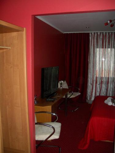 a hotel room with a bedroom with red walls and a television at Kardamon in Żary