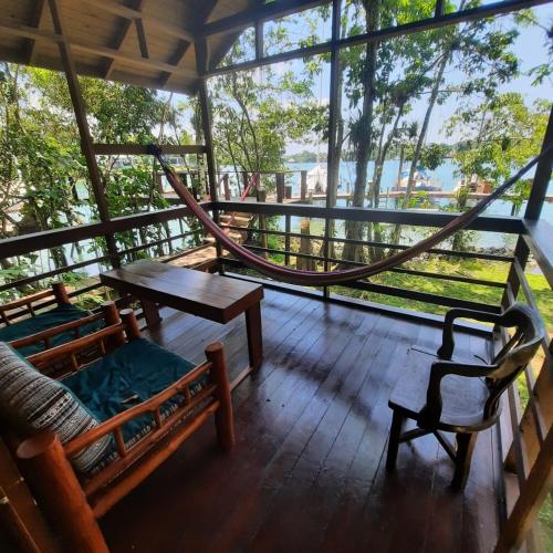 a porch with a hammock and a table and chairs at Tortugal Boutique River Lodge in Rio Dulce