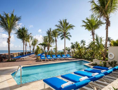 a pool with blue lounge chairs and palm trees at Condado Vanderbilt Hotel in San Juan