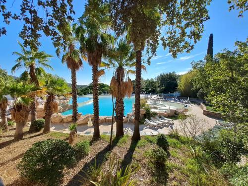 un complexe avec une piscine et des palmiers dans l'établissement La villa Charles Grimaud Les Restanques Golf de Saint Tropez, à Grimaud