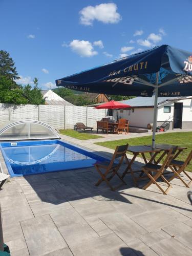 a swimming pool with a table and an umbrella at Wellness Villa Diana in Boldogkőváralja