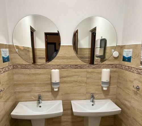 a bathroom with two sinks and two mirrors at Dorul Pescarului in Curtea de Argeş