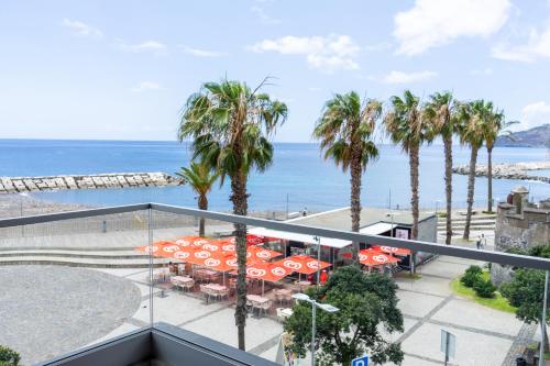a balcony with tables and umbrellas and the beach at Flag Hotel Madeira - Ribeira Brava in Ribeira Brava
