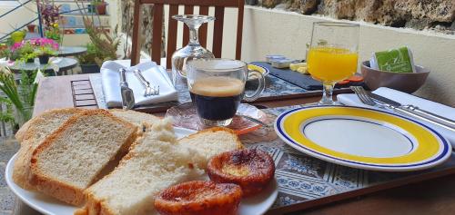 a table with a plate of bread and a glass of orange juice at A-Típica GuestHouse in Ponta Delgada