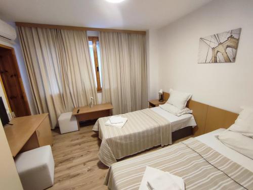um quarto de hotel com duas camas e uma secretária em Longoz em Bliznatsi