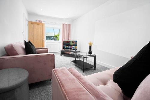 een woonkamer met 2 roze banken en een televisie bij Cosy 3 Bed House/Free Parking/Fast Wi-Fi/Sleeps 8 in Bilston