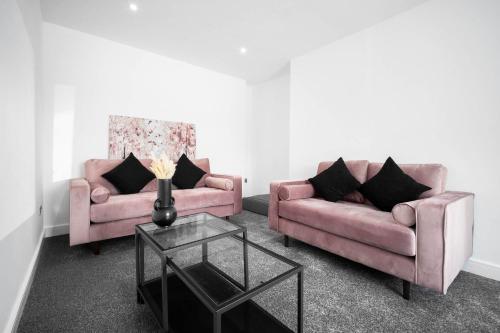 a living room with two pink couches and a table at Cosy 3 Bed House/Free Parking/Fast Wi-Fi/Sleeps 8 in Bilston