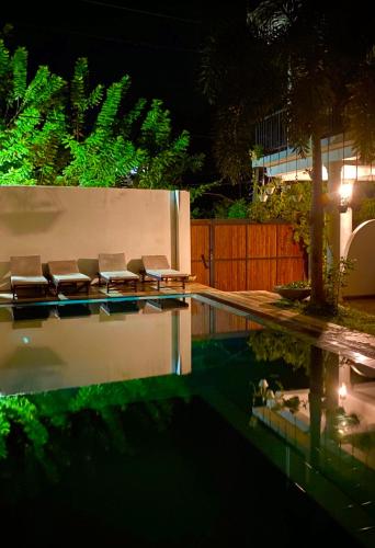 a pool with chairs next to a house at night at Kalu mirissa in Mirissa
