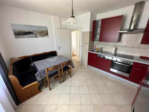 eine Küche mit roten Schränken und einem Tisch darin in der Unterkunft Apartma Zonta in Sečovlje