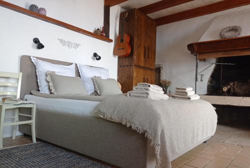 Bett mit weißen Kissen und Gitarre in einem Zimmer in der Unterkunft Casa Delle Olive in Mošćenička Draga