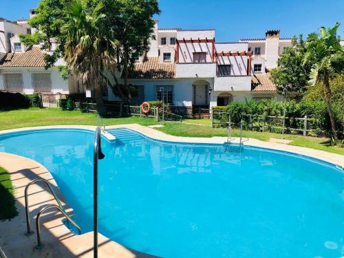 une grande piscine bleue en face d'une maison dans l'établissement Las Lagunetas de Cádiz, à Cadix