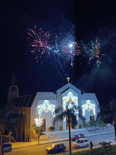 a church with fireworks exploding in the sky at night at "Appartamento del Mare Gliaca" con vista Isole Eolie,ampia terrazza,wifi e parcheggio gratuito in Piraino