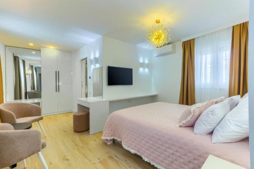a white bedroom with a bed and a tv at Irini Luxury Rooms in Split