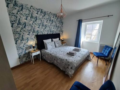ein Schlafzimmer mit einem Bett und einem blauen Stuhl in der Unterkunft Le TROPICA Appartement 2 chambres, plein Sud centre ville de VITRÉ in Vitré