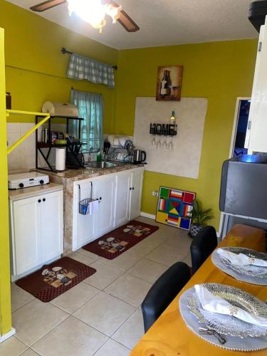 a kitchen with green walls and white cabinets and a table at jermaines onestop in Portmore