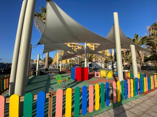 un parco giochi con una recinzione colorata di fronte a un edificio di Casa Isa - Aire acondicionado - Piscina - Candelaria - Tenerife a Candelaria