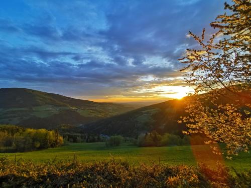 a sunset in the mountains with a green field at Alpengasthof Fernblick in Mönichkirchen