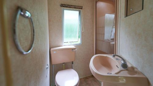 派拉克CAMPING LES PAILLOTES的带水槽、马桶和窗户的浴室