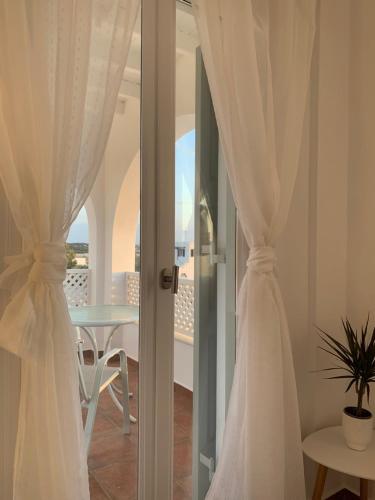 Habitación con cortinas blancas, mesa y balcón. en Sea and Salt Naxos 3, en Kastraki Naxou