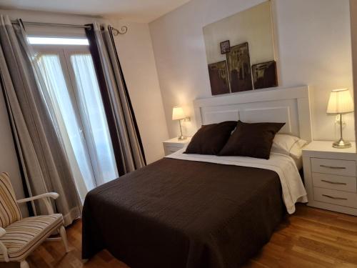 a bedroom with a bed and a chair and a window at Apartamento Torres in Valencia