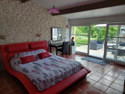 1 dormitorio con cama roja y pared de ladrillo en Detente au pays de Lauzun en Saint-Colomb-de-Lauzun