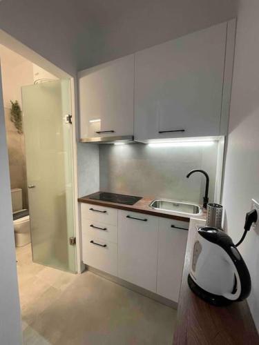 una pequeña cocina con armarios blancos y fregadero en Designed Central Apartment, en Volos