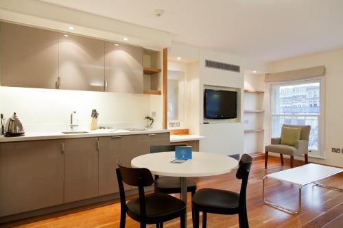a kitchen with a table, chairs, and a television at Blueprint Living Apartments -Turnmill Street in London