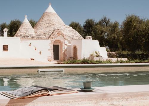 um livro aberto sobre uma mesa ao lado de uma piscina em Trullo EVO con piscina privata em Ostuni