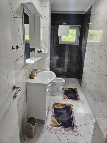 een witte badkamer met een wastafel en een toilet bij Golden Sky in Cazin