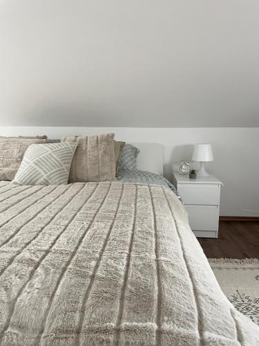 a white bedroom with a bed and a night stand at Stari grad 2 in Valjevo