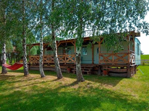 a house with a hammock in a yard with trees at Brzozowa Polana in Budry