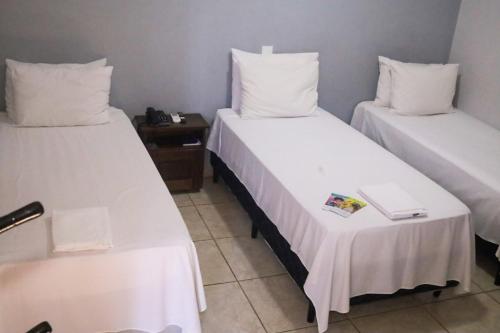 a room with two beds and a table with a book at Shellter Hotel in Holambra