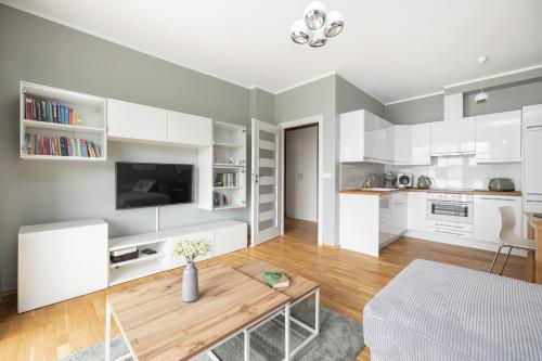 a living room with white cabinets and a table at Apartament REZYDENCJA MARINA in Gdańsk