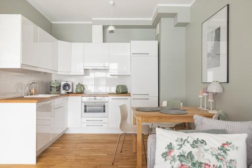 a kitchen with white cabinets and a wooden table at Apartament REZYDENCJA MARINA in Gdańsk