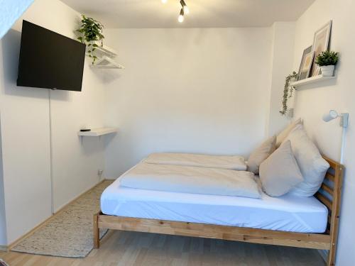 a bed in a room with a tv on a wall at NAMI - ROBIN - Helle Apartments mitten in der Stadt in Memmingen