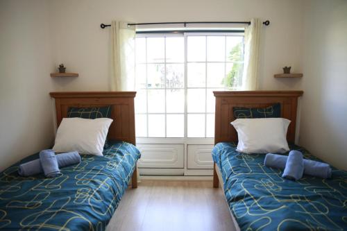 two beds in a room with a window at Casa Do Shon in Óbidos