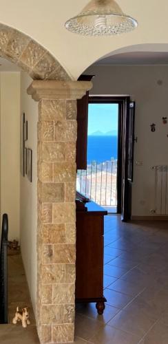 a room with a stone fireplace with a view of the ocean at Calacta casa mia in Caronia